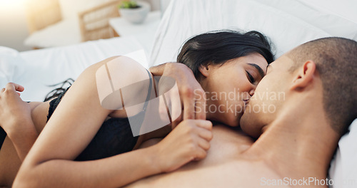 Image of Happy couple, relax and kiss on bed for love, morning or romance in embrace, trust or care at home. Young man and woman smile lying in bedroom for intimacy, passion or bonding together at house