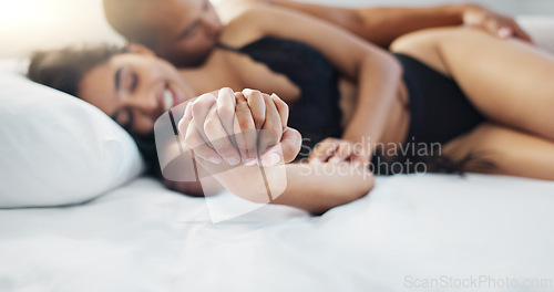 Image of Couple, holding hands and wake up in bed with happy, love and support together in a hotel. Bedroom, trust and bonding with marriage and commitment of people with a smile from relax and calm morning