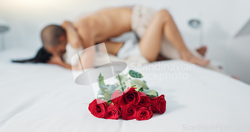 Image of Couple, red roses and lying on bed for love, anniversary or valentines day in romance, embrace or trust at home. Romantic man and woman in bedroom intimacy, passion or bonding with flowers at house