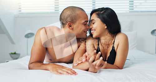 Image of Happy couple, relax and kissing on bed for intimacy, morning romance or love in embrace, trust or care at home. Young man and woman smile lying in bedroom for passion or bonding together at house