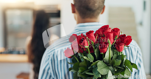 Image of Happy couple, red roses and kiss for surprise, anniversary or valentines day in kitchen at home. Face of young man and woman smile with flowers for romantic gift, love or care in celebration at house