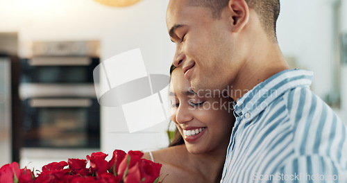 Image of Happy couple, red roses and kiss for surprise, anniversary or valentines day in kitchen at home. Face of young man and woman smile with flowers for romantic gift, love or care in celebration at house