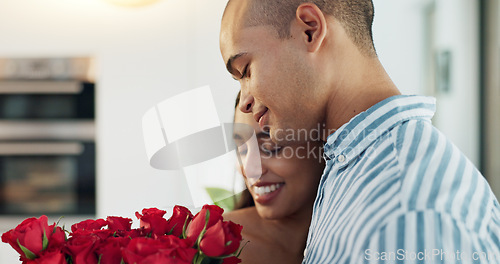 Image of Happy couple, red roses and kiss for surprise, anniversary or valentines day in kitchen at home. Face of young man and woman smile with flowers for romantic gift, love or care in celebration at house
