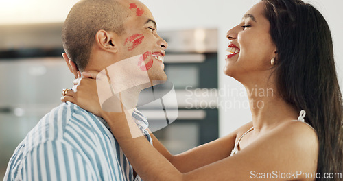 Image of Happy couple, love and kiss with lipstick for fun date and playful at home in intimacy, romance and valentines day. Lover, woman and man in kitchen or house with lip print on cheek for anniversary