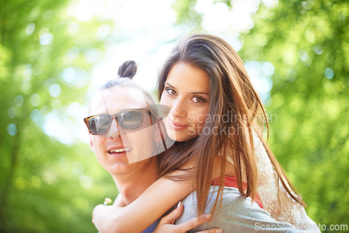 Image of Love, piggyback and couple in a park with support, care or bonding on date in nature together. Face, romance and people embrace in a forest for travel, vacation or day off trip, holiday or having fun