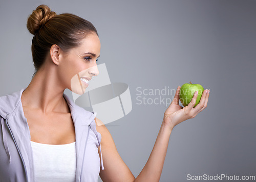 Image of Happy, health and woman in studio with apple, offer or mockup for fiber or gut health on grey background. Nutrition, space and model with fruit for weight loss help, nutrition or raw superfoods diet