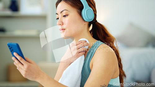 Image of Woman, phone and yoga with rest, towel and music while sitting, floor and relax in living room. Girl, headphone and smartphone for streaming, video or reading while taking break, training or fitness