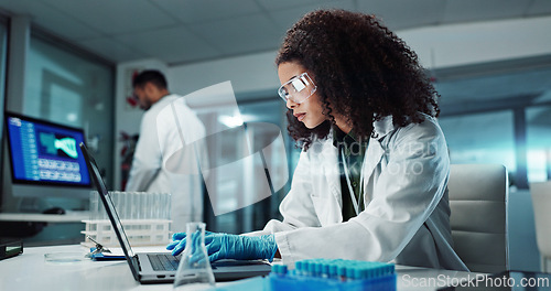 Image of Scientist, woman and typing on laptop with test tube for chemistry, research or experiment at lab. Science, computer and serious medical professional in development of cure, biotechnology or study