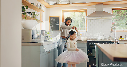 Image of Dance, ballet and girl with mother in a kitchen together or mom support child and playing as a dancer or ballerina. Tutu skirt, mommy and woman dancing, bonding or spin with kid in house or home