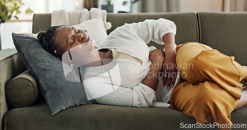 Image of Home, pain and black woman on a couch, cramps and stomach with sickness, suffering and disease in the living room. African person, apartment and girl with abdominal problem, tummy ache and period