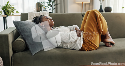 Image of Home, pain and black woman on a couch, cramps and stomach with sickness, suffering and disease in the living room. African person, apartment and girl with abdominal problem, tummy ache and period