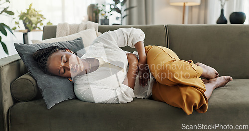 Image of Home, pain and black woman on a couch, cramps and stomach with sickness, suffering and disease in the living room. African person, apartment and girl with abdominal problem, tummy ache and period