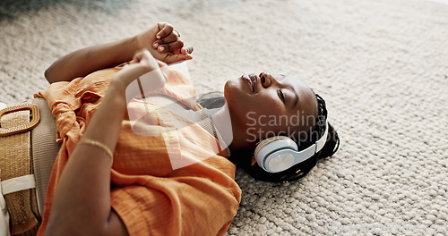 Image of Headphones, relax and young woman on the floor in the living room listening to music or radio at modern apartment. Dancing, smile and young African female person streaming song in the lounge at home.