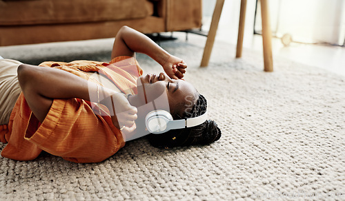 Image of Headphones, relax and young woman on the floor in the living room listening to music or radio at modern apartment. Dancing, smile and young African female person streaming song in the lounge at home.