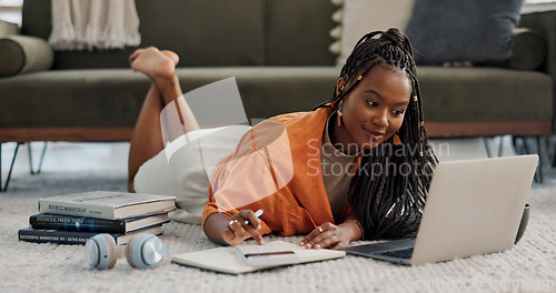 Image of Laptop, happy and woman writing notes on the floor in the living room of modern apartment. Technology, smile and young African female university student studying on a computer in the lounge at home.