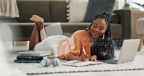 Image of Laptop, happy and woman writing notes on the floor in the living room of modern apartment. Technology, smile and young African female university student studying on a computer in the lounge at home.