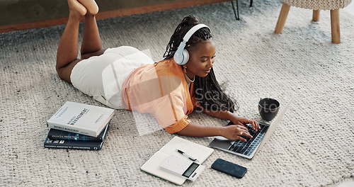 Image of Laptop, headphones and young woman on the floor in living room of modern apartment. Tech, smile and young African female university student study and listen to music on computer in lounge at home.