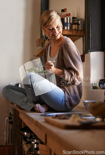 Image of Happy, woman and eating salad in kitchen at home, nutrition and fresh leafy greens for healthy diet. Vegetables, bowl and smile of hungry person with food, lunch or organic vegan meal for wellness