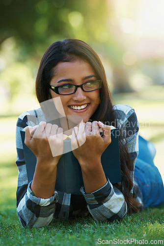 Image of Happy woman, student and relax with book for reading, literature or studying on green grass. Young nerd, geek or female person with smile and glasses for chapter, learning or outdoor story in nature