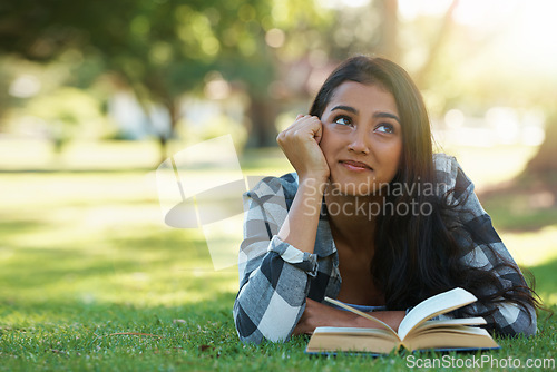 Image of Happy woman, student and thinking with book for reading, literature or studying on green grass. Young or thoughtful female person with smile in wonder for chapter, learning or outdoor story in nature