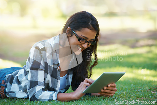 Image of College, woman and typing on tablet in park with research, project or learning outdoor on campus. University, student and girl reading online with ebook, education and studying on grass in garden