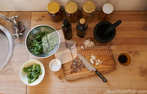 Image of Salad, knife and ingredients on kitchen counter or cooking as leafy greens or nutrition, health or wellness. Wooden board, garlic and walnuts or spices as organic with lettuce, vegetables or top view