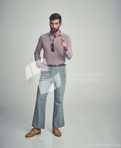 Image of Vintage, fashion and portrait of man with 70s retro aesthetic in gray background of studio. Smoking, pipe and serious person with confidence and pride in funky clothes and unique style from past