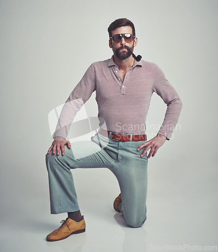 Image of Vintage, fashion and portrait of man with 70s retro aesthetic in gray background of studio. Smoking, pipe and person with confidence and pride in funky sunglasses, clothes and unique style from past