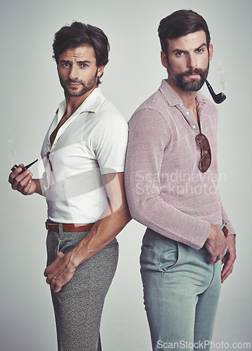 Image of Fashion, men and portrait or pipe in studio with vintage model, hipster outfit and confidence or serious expression. Friends, people and attitude with 70s style or retro clothes with white background