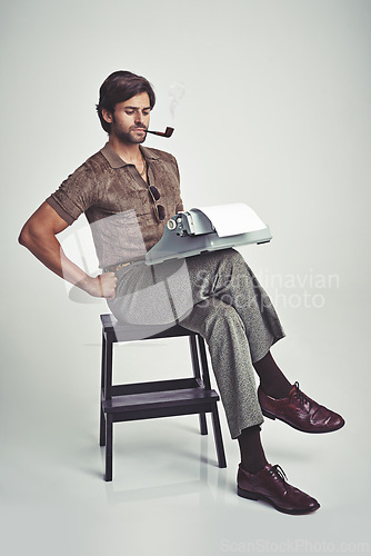 Image of Fashion, man and typewriter or pipe in studio with vintage model, hipster outfit and confidence on chair. Relax, person and reading with 70s style, calm expression and smoking with white background