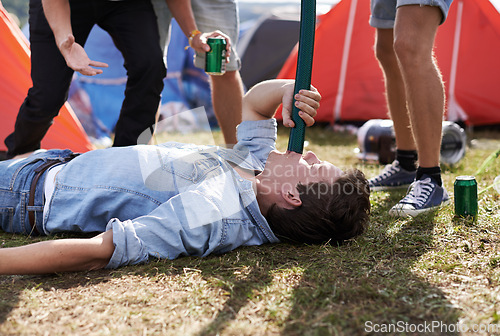 Image of Alcohol, drinking and funnel with man at festival, on ground for event, party or social gathering. Beer, grass and young drunk person with friends on grass or field outdoor at camp for celebration