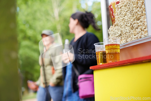 Image of Beer, popcorn and vendor at festival closeup outdoor with people on blurred background for event or party. Summer, food or snack with alcohol in plastic cup on counter for drinking and celebration