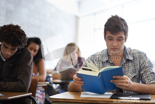 Image of University, book and man in classroom reading for development in learning, opportunity and future career. Education, knowledge and growth for college student in lecture, studying for exam or test.