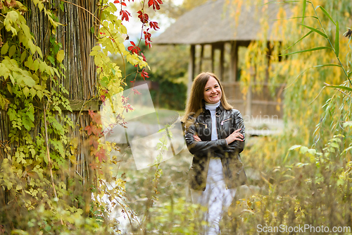 Image of A young beautiful girl walks in the forest near a pond and looks happily into the frame