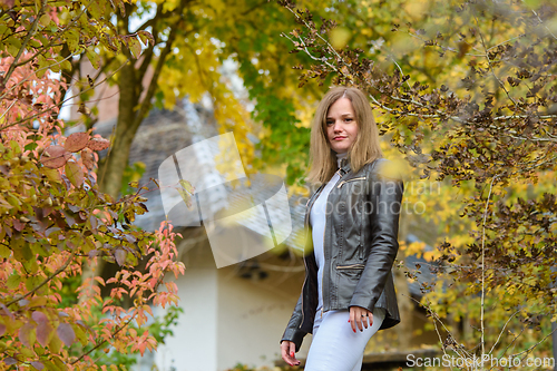 Image of Young beautiful girl in casual clothes against the background of beautiful foliage and a private house