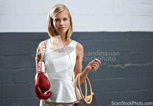 Image of Woman, portrait and bag with boxing gloves, makeup and stylish outfit by wall background. Female person, blush and eyeshadow for sport match, reflection and fashion to prepare for post interview