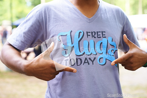 Image of Tshirt, outdoor and man with fun, pointing and free hugs today with party and promotion. Motivational slogan, person and guy with casual outfit and stylish clothes with sunshine and summer break