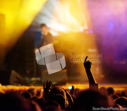 Image of Concert, audience and hands in crowd with band for music festival, night club and dancing with light. Disco, party and people with signs, gesture or performance at rock event with stage entertainment