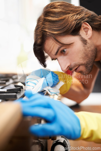 Image of Man, kitchen and serious in cleaning a countertop with cloth, spring clean and polishing for hygiene at home. Stove, responsibility and routine to remove dirty stains, germs with water and soap