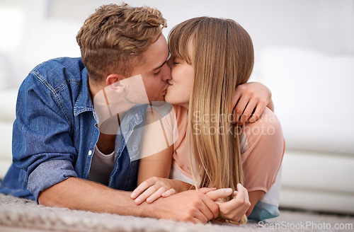 Image of Couple, kiss and relax on floor, living room and happy with love, joy and together in relationship. Lovers, romantic and date with partner, content and touch with hands, devotion and lying on mat