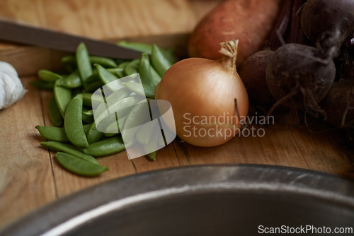 Image of Vegetables, onion and wooden board for cooking lunch, dish and nutrition for diet at home. Wellness, health and organic food with meal, vegetarian and green ingredients for vegan salad in a kitchen