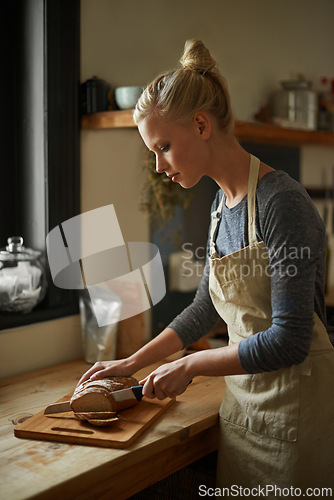 Image of Bakery, kitchen and woman with knife on bread, cutting on board and cooking gluten free food for breakfast. Fresh, loaf and chef in restaurant with healthy rye in preparation process of brunch