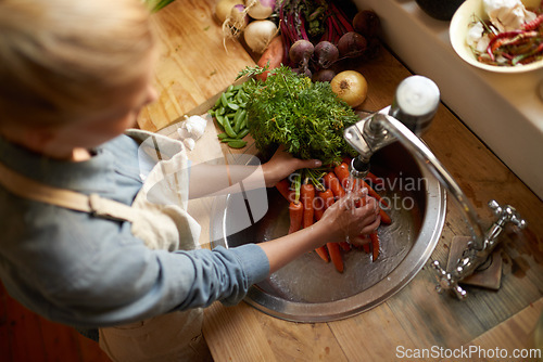 Image of Person, sink and cleaning carrot in kitchen, health and hygiene with cooking food and top view. Vegetables, nutrition and organic for dinner meal, vegan or vegetarian with chef washing produce