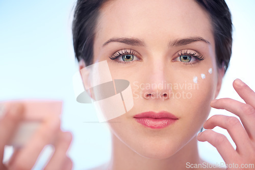 Image of Portrait of woman, wellness or face cream for skincare, beauty or cosmetics on blue background. Antiaging, studio or model with product application or glow for lotion, dermatology or facial treatment