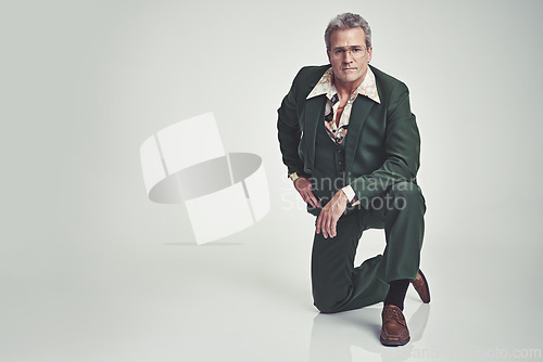 Image of Portrait, fashion and senior man in style or business outfit on a gray studio background. Mature, male person or model posing with knee on floor in stylish formal clothing or suit on mockup space