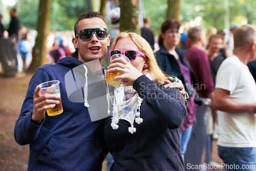 Image of Drinks, happy and couple of friends at music festival, concert or party for outdoor rave or techno celebration. Portrait of young people, audience or crow in forest with beer or alcohol for holiday