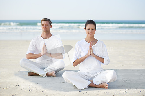 Image of Lotus, yoga and couple on beach in morning for fitness, exercise and mindfulness with prayer hands. Nature, love and man and woman by ocean for meditation, wellness and healthy body outdoors together