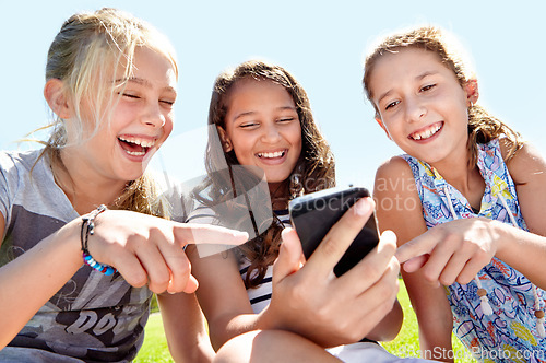 Image of Children, friends and cellphone in park or laughing at funny post on social media for humor, online or joke. School kids, girls and pointing at smartphone in nature or reading meme, bonding or fun
