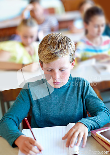 Image of Student, boy and writing notes for learning in classroom, book and problem solving at school. Male person, child and study information for exam prep in notebook, solution and journal for assessment