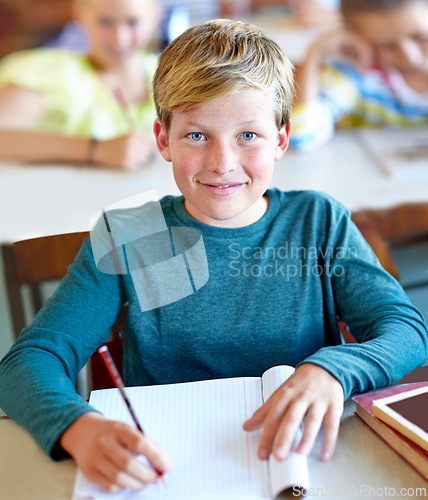 Image of Student, portrait and boy writing notes for learning in classroom, book and problem solving at school. Male person, child and information for exam prep in notebook, solution and journal for test